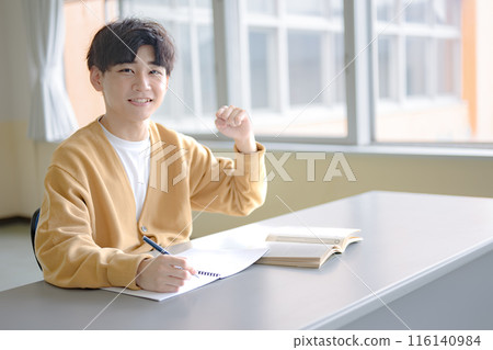 A young man doing a fist pump while studying A young man doing a fist pump while studying 116140984