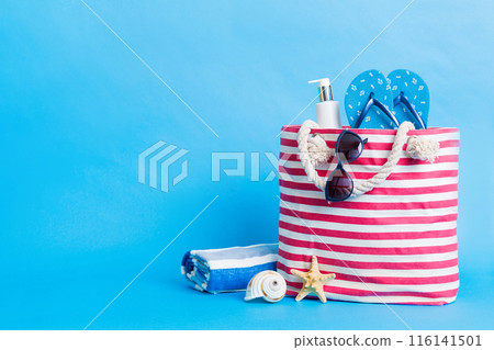 Stylish bag with beach accessories . Summer holiday concept. Top view of beach bag with sunscreen cream with space for text 116141501