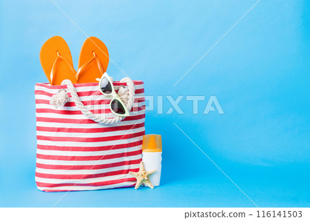 Stylish bag with beach accessories . Summer holiday concept. Top view of beach bag with sunscreen cream with space for text 116141503