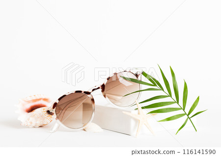 sunglasses with seashell lying on table background. Sunglasses on summer background. Top view flat lay with copy space for text 116141590