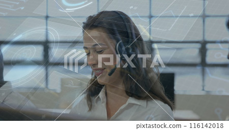 A young Caucasian woman wearing headset looking at computer screens 116142018