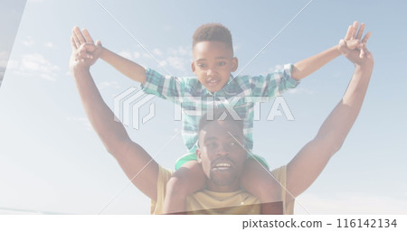 African American father lifting son on shoulders, both smiling under clear sky African American father lifting son on shoulders, both smiling under clear sky 116142134