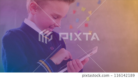 In school, boy in uniform using a tablet, colorful letters on wall behind In school, boy in uniform using a tablet, colorful letters on wall behind 116142189