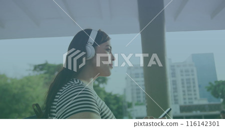 Caucasian woman wearing headphones, holding smartphone 116142301