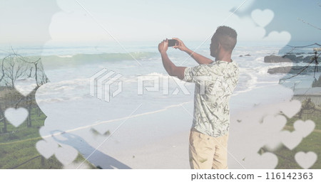 African American male capturing beach scenery with smartphone African American male capturing beach scenery with smartphone 116142363