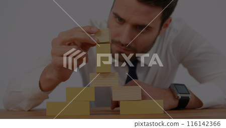 Caucasian chef wearing white shirt building tower from wooden blocks Caucasian chef wearing white shirt building tower from wooden blocks 116142366