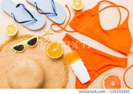 Swimming pool accessories concept. Top view of beach items on table, bright bikini, straw hat, and sunscreen skincare cream. Colorful beach wear. top view Flat lay, copy space Swimming pool accessories concept. Top view of beach items on table, bright bikini, straw hat, and sunscreen skincare cream. Colorful beach wear. top view Flat lay, copy space 116142985