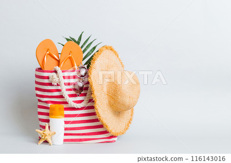 Stylish bag with beach accessories . Summer holiday concept. Top view of beach bag with sunscreen cream with space for text 116143016