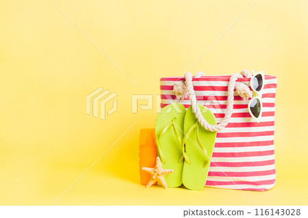 Stylish bag with beach accessories . Summer holiday concept. Top view of beach bag with sunscreen cream with space for text 116143028