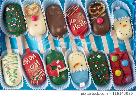 Christmas dessert. Sweet food. Cheesecake on a stick in the shape of ice cream. Children's treat in winter. Candy Christmas tree, snowman, deer and Santa Claus. Gingerbread cookies 116143080