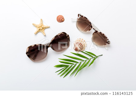 sunglasses with seashell lying on table background. Sunglasses on summer background. Top view flat lay with copy space for text 116143125