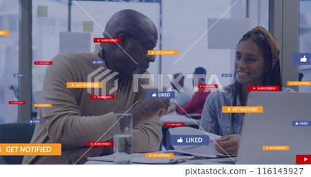 A group of diverse business colleagues talking and using laptops in an office 116143927