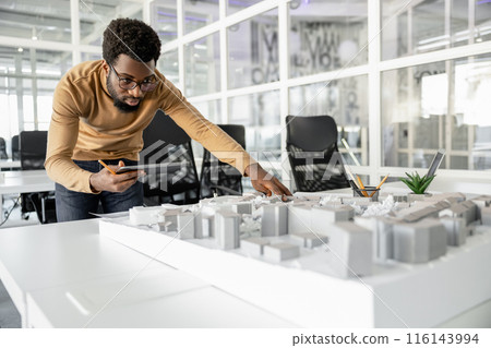 Young man in casual clothes working on miniature and looking involved Young man in casual clothes working on miniature and looking involved 116143994