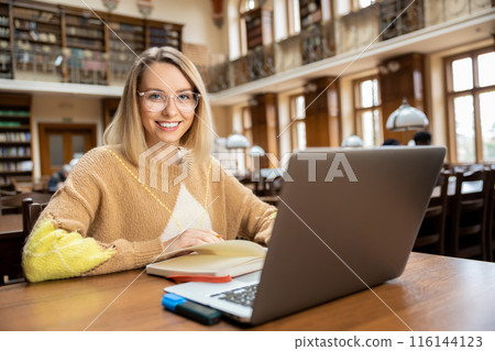 Smiling pretty woman working in the library Smiling pretty woman working in the library 116144123