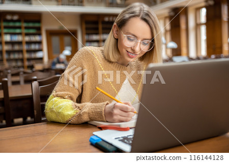 Smiling pretty woman working in the library Smiling pretty woman working in the library 116144128