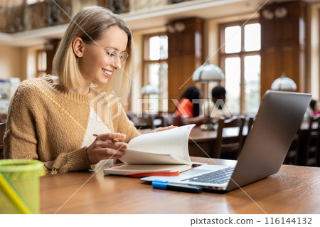 Smiling pretty woman working in the library Smiling pretty woman working in the library 116144132