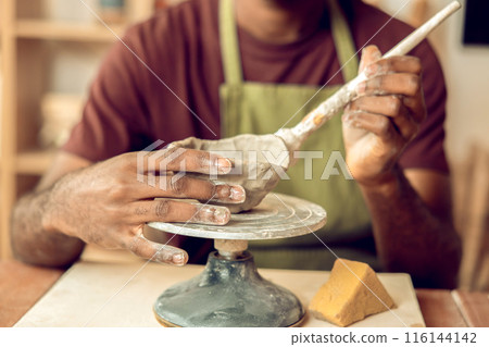 Male sculptor working on a new clay mug in his office Male sculptor working on a new clay mug in his office 116144142