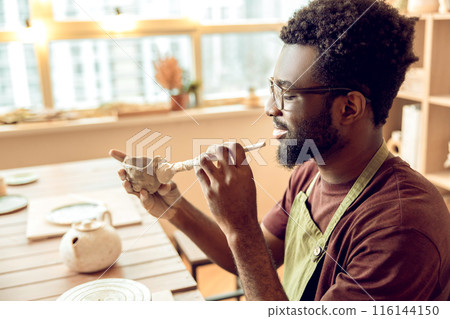 Male sculptor working on a new clay mug in his office 116144150