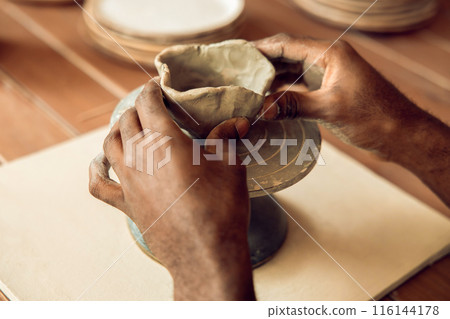 Close up picture of sculptors hands working with a clay mug 116144178