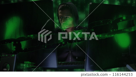 A young Caucasian professional wearing dark hoodie, focusing on glowing screens 116144253