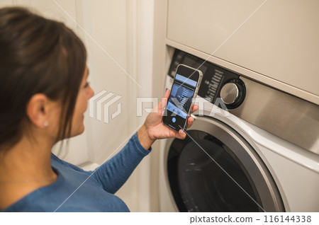 Woman making a picture of a washing machine before using it 116144338