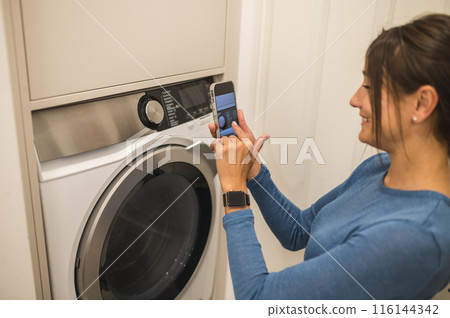 Woman making a picture of a washing machine before using it 116144342