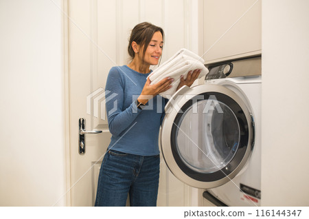Woman smelling newly washed towels and looking contented Woman smelling newly washed towels and looking contented 116144347