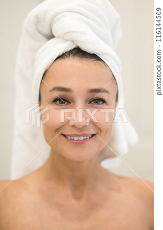Cute caucasian woman with towel on her head looking contented Cute caucasian woman with towel on her head looking contented 116144509