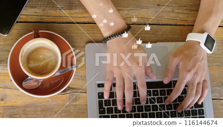 A person wearing smartwatch is typing on a laptop next to a coffee cup 116144674