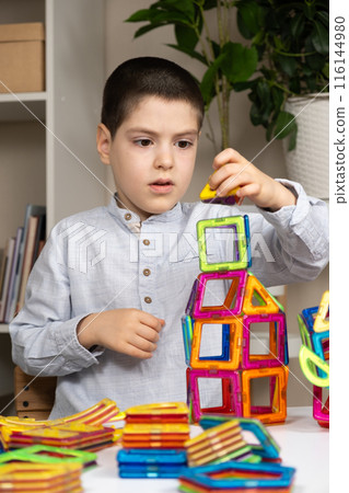 A six-year-old boy plays with a magnetic construction set. Toys for children to develop imagination. 116144980