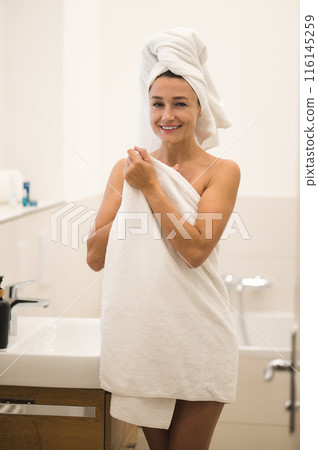 Slim young woman in white towel standing in the bathroom 116145259