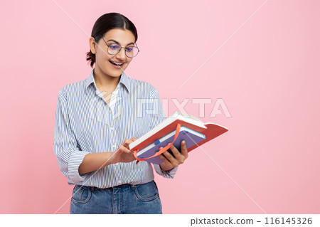 Beautiful girl in casual shirt holding organizer reading notes in paper notebook 116145326