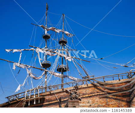mast with sails on ancient wooden pirate ship on background of blue sky mast with sails on ancient wooden pirate ship on background of blue sky 116145389