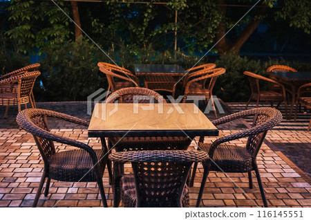 wooden tables and wicker chairs in an outdoor cafe in evening wooden tables and wicker chairs in an outdoor cafe in evening 116145551