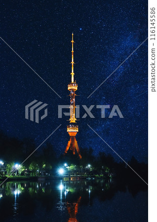 illuminated TV tower at night in Tashkent in Uzbekistan with a reflection in water of river under blue sky with stars 116145586