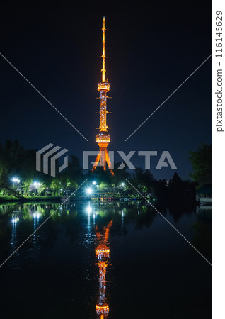 TV tower illuminated at night in Tashkent in Uzbekistan with a reflection in water of river on background of a dark blue sky 116145629