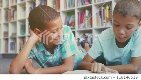 Two boys sitting on floor, reading together in colorful library 116146519