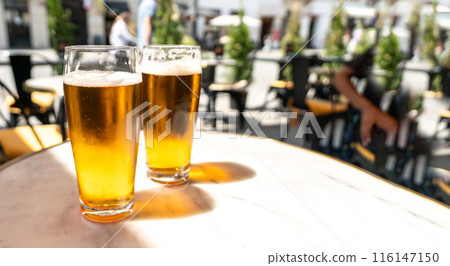 Beer glass in sunny day, cold pint glass with remaining beer on outdoor table, cool condensation 116147150