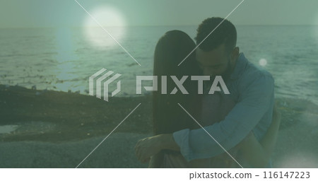 Image of spots of light against african american couple hugging each other at the beach 116147223