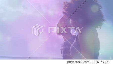 Image of spots of light against african american couple walking together at the beach 116147232