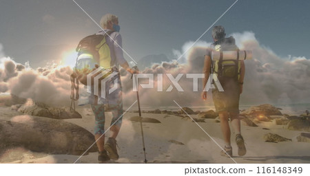 Caucasian couple hiking on rocky beach, carrying backpacks 116148349