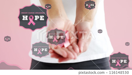Image of hope text with hands of woman holding pink breast cancer ribbon, on pink background 116148530