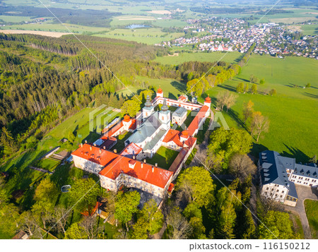 Aerial view of Hora Matky Bozi Monastery, located in Dolni Hedec near Kraliky, Czechia. The monastery is situated on a hilltop surrounded by lush green fields and forests. Aerial drone photography. 116150212