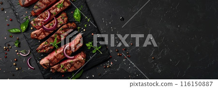 Beef grilled meat, black stone background, spices, onion, herbs. Top view Banner. Fresh red meat with pepper, salt for grilling on dark cutting board. Prime fillet. Food magazine style. Chief menu BBQ 116150887