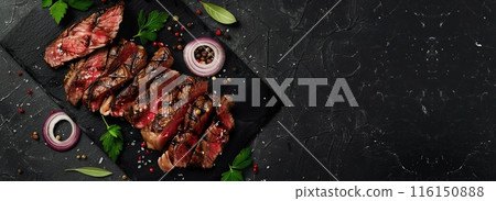 Beef grilled meat, black stone background, spices, onion, herbs. Top view Banner. Fresh red meat with pepper, salt for grilling on dark cutting board. Prime fillet. Food magazine style. Chief menu BBQ Beef grilled meat, black stone background, spices, onion, herbs. Top view Banner. Fresh red meat with pepper, salt for grilling on dark cutting board. Prime fillet. Food magazine style. Chief menu BBQ 116150888