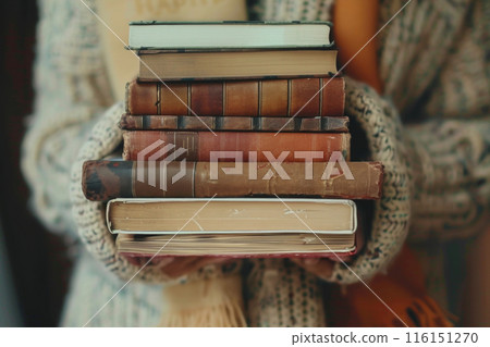A girl on the street holds a stack of books in front of her 116151270