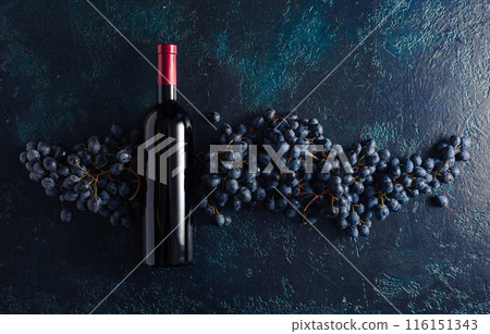 Bottle of red wine and grapes on a blue vintage background. 116151343