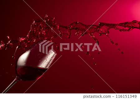 Glass and red wine splash on a dark red background. Glass and red wine splash on a dark red background. 116151349