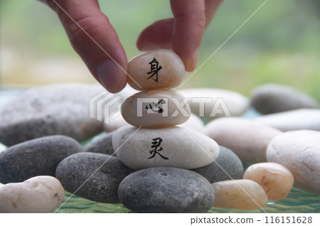 Hand placing Zen stone with body, mind and spirit in Chinese character. Zen concept 116151628