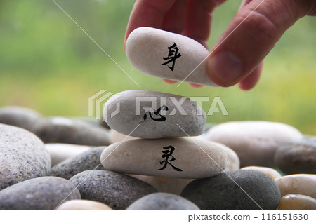 Hand placing Zen stone with body, mind and spirit in Chinese character 116151630